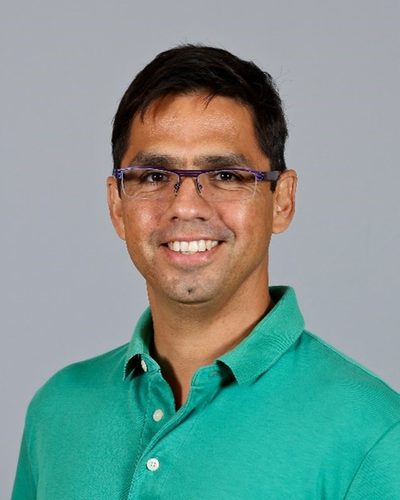 headshot of a man in a green shirt and glasses