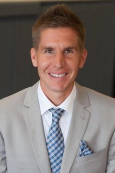 headshot of Peter wearing a grey suit and blue patterned tie.